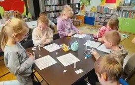 Dzieci przy stole uzupełniają zwierzątkowe sudoku naklejając odpowiednie elementy w puste kwadraciki.