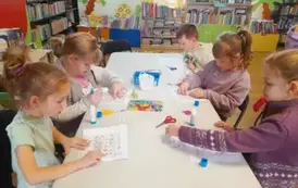 Dzieci przy stole uzupełniają zwierzątkowe sudoku naklejając odpowiednie elementy w puste kwadraciki.