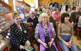 Czytelnicy siedzą na krzesłach i patrzą w kierunku autora.