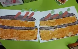 Na stoliku leżą dwie prace plastyczne dzieci w postaci tortu przyozdobionego stempelkami z marchewek.