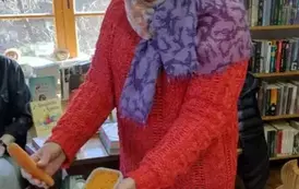 Prowadząca pokazuje dzieciom marchewkę i potartą marchewkę w pojemniku.