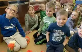 Dzieci siedzą na dywanie i siedziskach i słuchają bajki.