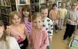 Dzieci stoją w parach w bibliotece przygotowując się do wyjścia