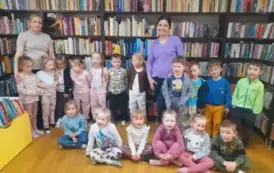 Dzieci stoją w grupie razem z Panią wychowawczynią i z bibliotekarką.