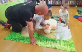 Chłopiec odchyla usta fantomowi, obok prezes i drugi chłopiec się przyglądają.