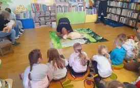 Dzieci siedza na dywanie, a z przodu prezes OSP pokazuje sztuczne oddychanie na fantomie.