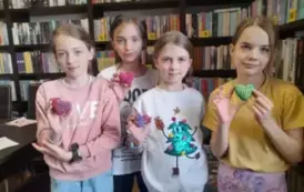 Cztery dziewczynki stoją razem i pokazują swoje pomalowane z gipsu serduszka.