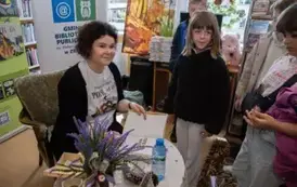 Anna Sakowicz przy stoliku podpisuje dedykacje na książce. Dzieci stoją obok Niej z zamiarem kupienia książeczki.