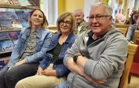 Dwie Panie i dw&oacute;ch Pan&oacute;w siedzą na krzesłach i się uśmiechają.