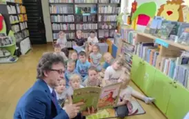 Dzieci siedzą na dywanie i słuchają bajki, kt&oacute;rą czyta im sołtys wsi Pinczyn. 