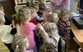 Dzieci gromadnie stoją przy Pani Agnieszce, kt&oacute;ra częstuje cukierkami.