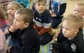 Dzieci siedzą na dywanie i słuchają bajki, kt&oacute;rą gościnnie czyta Pani Małgorzata Milewska