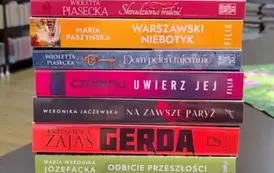 Na stole w pionowym rzędzie są połozone nowe książki z widocznymi tytułami