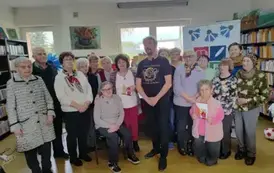 Wszyscy seniorzy biorący udział w spotkaniu stoją razem z Panem Pilarskim w grupie.