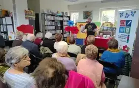 Widok z tyłu sali, krzesła zajęte przez naszych gości. Z przodu Pan Pilarski recytuje wiersze gestykuląc rękami.