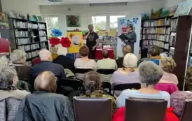 Z przodu bibliotekarka z Pinczyna wita Piotra Pilarskiego. Wszystkie krzesła są zajęte przez senior&oacute;w.