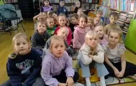 Dzieci siedzą na siedziskach i słuchają bajki.