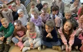 Wszystkie dzieci siedzą razem na dywanie.