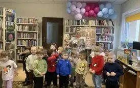 Wszystkie dzieci stoją w grupie razem z bibliotekarką, kt&oacute;ra trzyma dwie bajki o misiach.