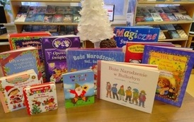 Na stole są wystawione bajki świąteczne i mała biała choinka