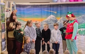 Na środku stoi siedmioro dzieci razem z reniferem i elfem, kt&oacute;ry im po kolei zadaje pytania.