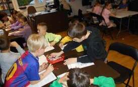 Dzieci przy stołach uzupełniają świąteczne karty pracy