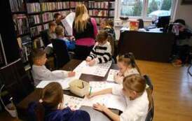 Dzieci siedzą przy stole i piszą list do Świętego Mikołaja i uzupełniają inne karty pracy.