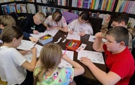 Dzieci przy stole rozwiązują krzyż&oacute;wki, hasła wpisują kredkami.