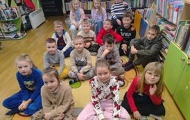 Duża grupa dzieci siedzi na dywanie i słucha opowieści kociewskich