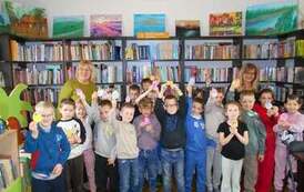 Uczniowie klasy 1 stoją razem z dwiema swoimi Paniami i trzymają wykejone pisanki z papieru