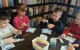 Dzieci przy stole wyklejają sudoku czyli w odpowiednie miejsca naklejaja kolorowe kosze na śmieci aby w pionie i w poziomie sie nie powtarzały.