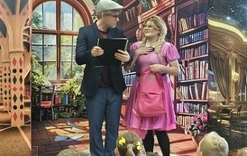 Kurtyna przedstawiająca bibliotekę, stoi Filmowy Feliks trzymając Księgę marzeń, obok stoi Zosia z rożową torebką i ma rękę prawą położone na "sercu"