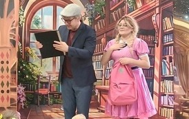 Kurtyna przedstawiająca bibliotekę, stoi Filmowy Feliks trzymając Księgę marzeń, obok stoi Zosia z rożową torebką i ma rękę prawą położone na "sercu"