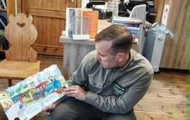 Leśnik czyta bajkę dzieciom "Lokomotywę". Książkę ma skierowaną obrazkami do dzieci.