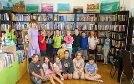 Dzieci stoją w grupie z bibliotekarką