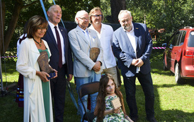 Na krześle siedzi dziewczynka i trzyma pudełko z napisem Perełka Kociewia, koło Niej stoi czterech meżczyzn i jedna kobieta. Kobieta i jeden z mężczyzn trzymają statuetki Ambsasador Kociewia.