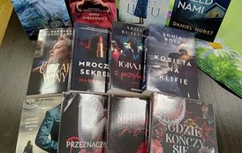 Na stole są wyłożone nowości wydawnicze z widocznymi tytułami