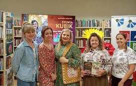 Cztery bibliotekarki stoją razem z pisarką pozując. Kierowniczka trzyma dwie książki. 
