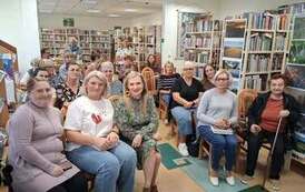 Wszystkie krzesła w bibliotece zajęte przez gości przybyłych na spotkanie autorskie