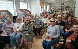 Wszystkie krzesła w bibliotece zajęte przez gości przybyłych na spotkanie autorskie