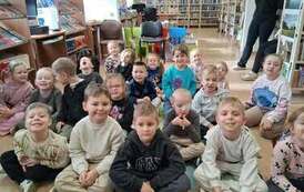 Duża grupa dzieci siedzi na dywanie w bibliotece