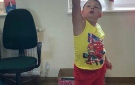 Chlopiec trzyma w g&oacute;rze rakietę odbijając papierową kulę.