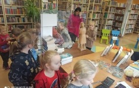 Kolejka dzieci podchodząca do biurka aby skorzystać z czytnika aby zapisać książkę.