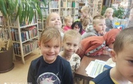 Kolejka dzieci ustawiona przy biurku w bibliotece.