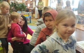 Kolejka dzieci ustawiona przy biurku w bibliotece.