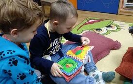 Dw&oacute;ch chłopc&oacute;w ogląda książeczkę pluszową.