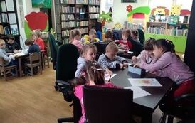 Trzy stoliki wypełnione dziećmi, kt&oacute;re kolorują kredkami misie.