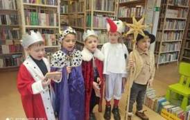Dzieci przebrane za trzech kr&oacute;li i pastuszk&oacute;w stoją w bibliotece z życzeniami świątecznymi.