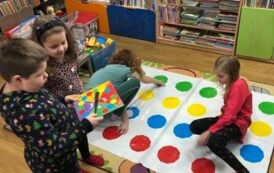 Czw&oacute;rka dzieci gra w rozłożoną na dywanie grę TWISTER.