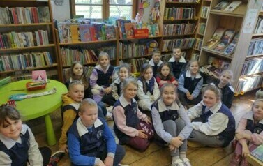 Dzieci siedzą na siedziskach i słuchają bajki czytanej przez bibliotekarkę.